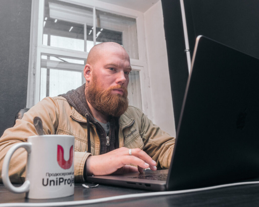 Артист работает за ноутбуком в студии продюсерского центра UniProject