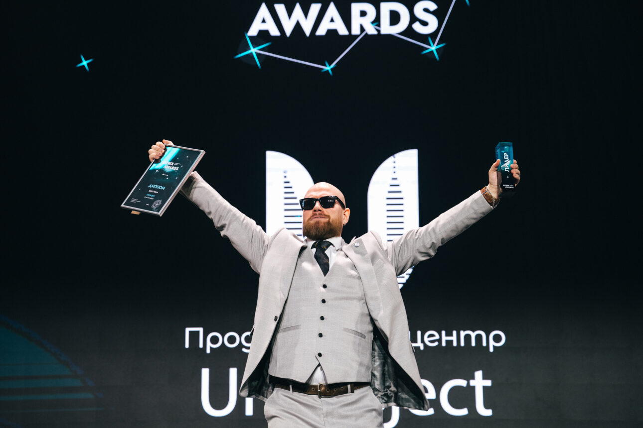 мужчина в белом костюме с наградой Взлет года UniProject
